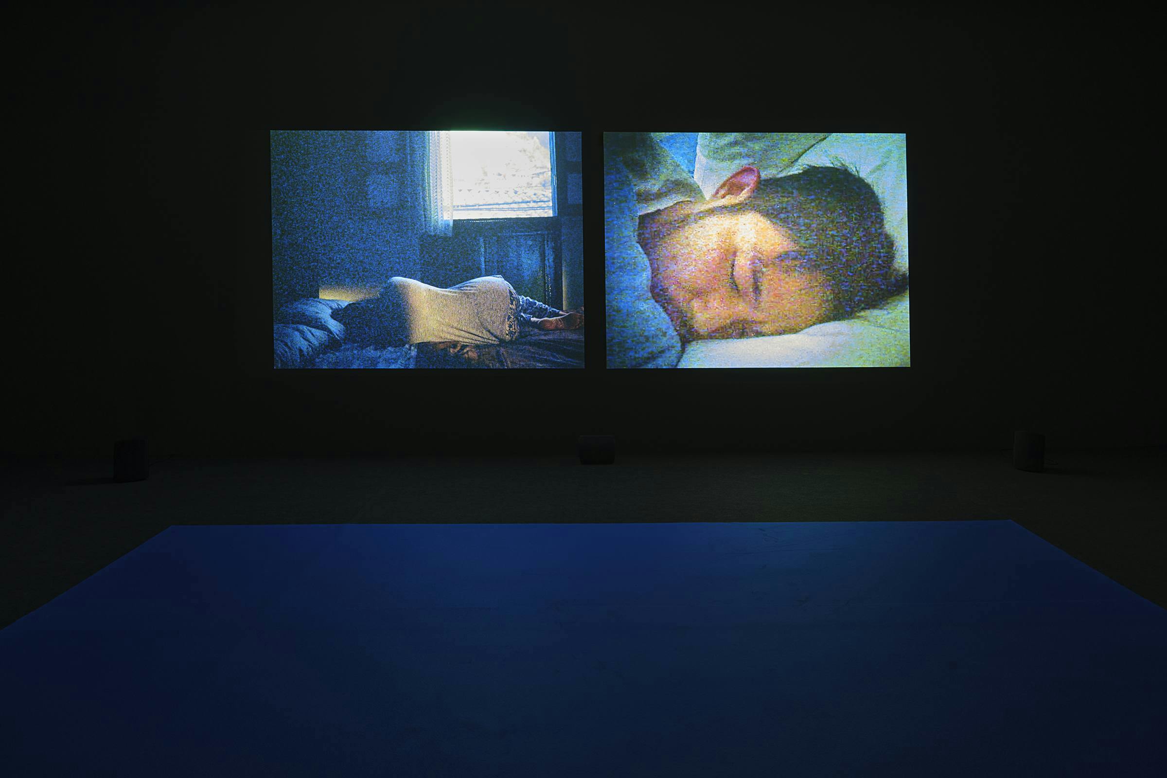 an image of the work Durmiente & async projected in a darkened space. The carpet is blue.