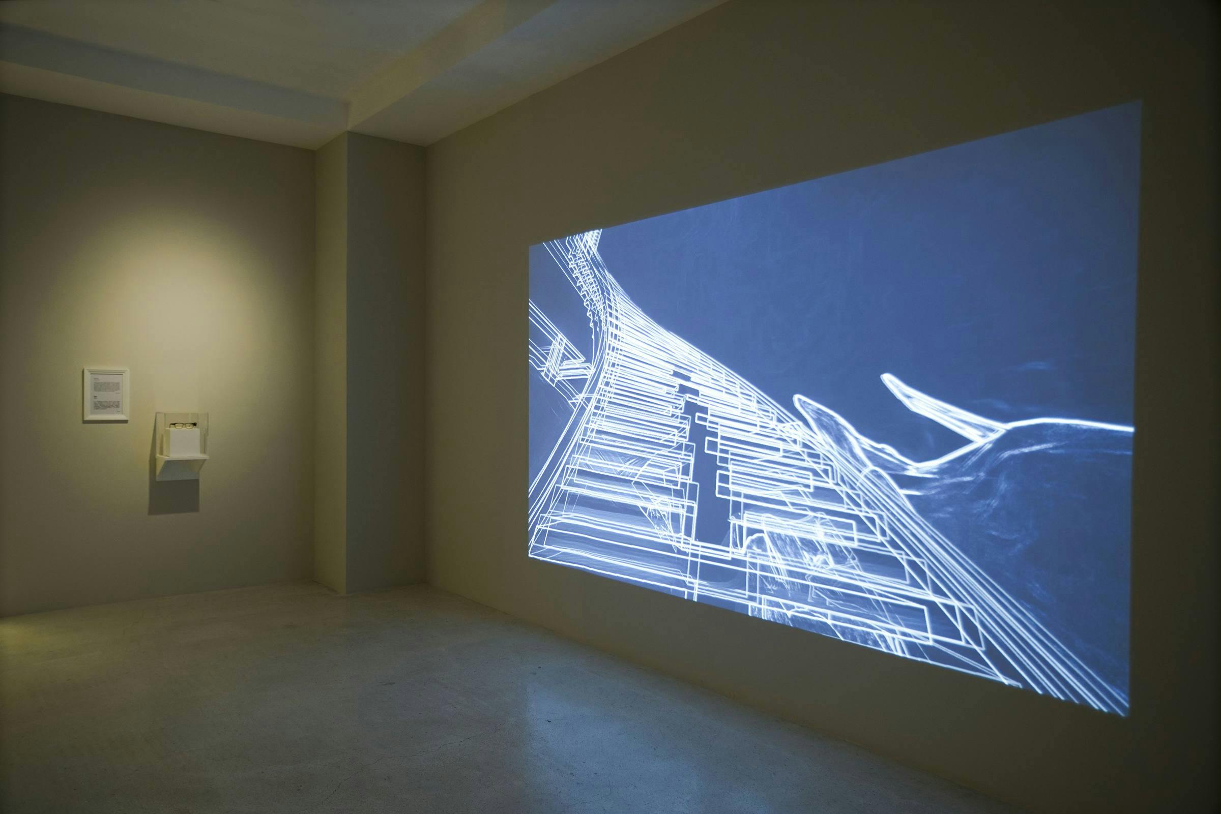 Image of a video being projected onto a concrete wall in a gallery space.