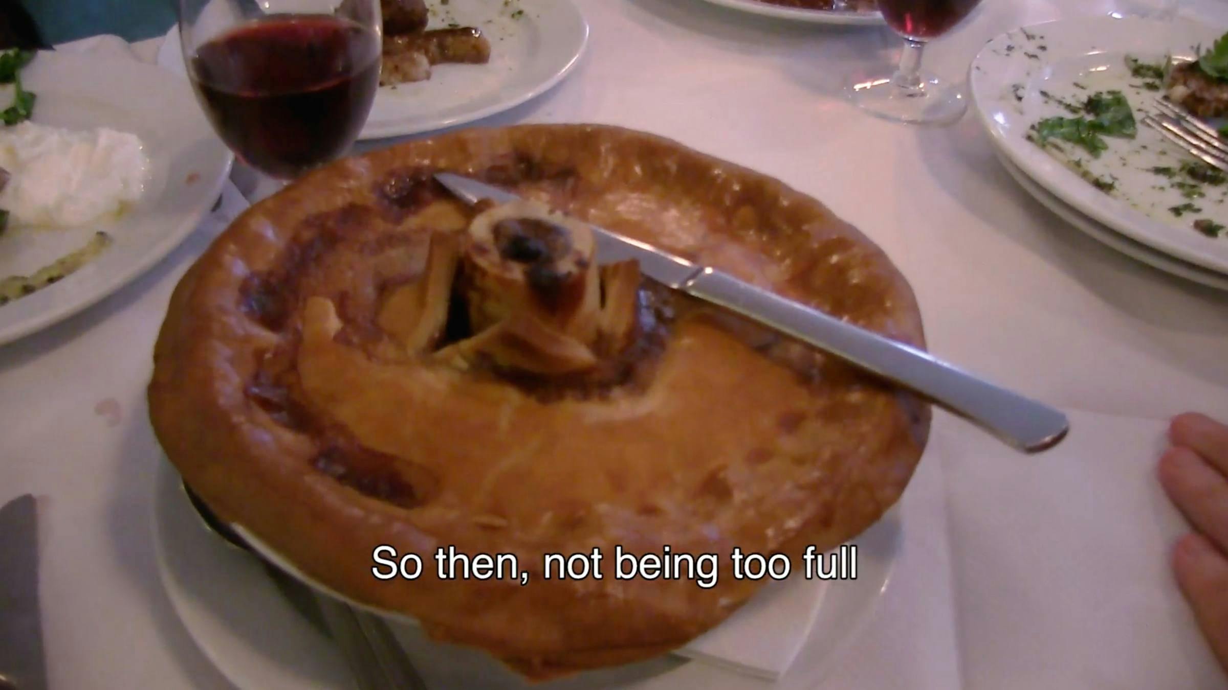 A pie sat on a table with a knife resting on top of it. 
