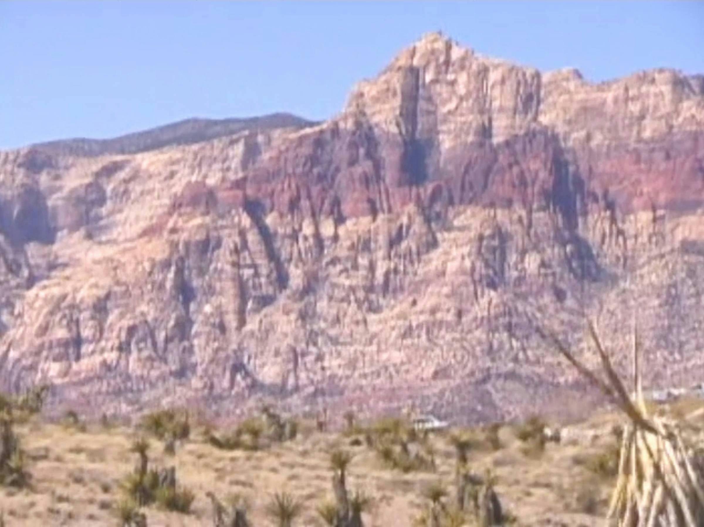 a image of mountains against a blue sky. Cacti are visible in the foreground