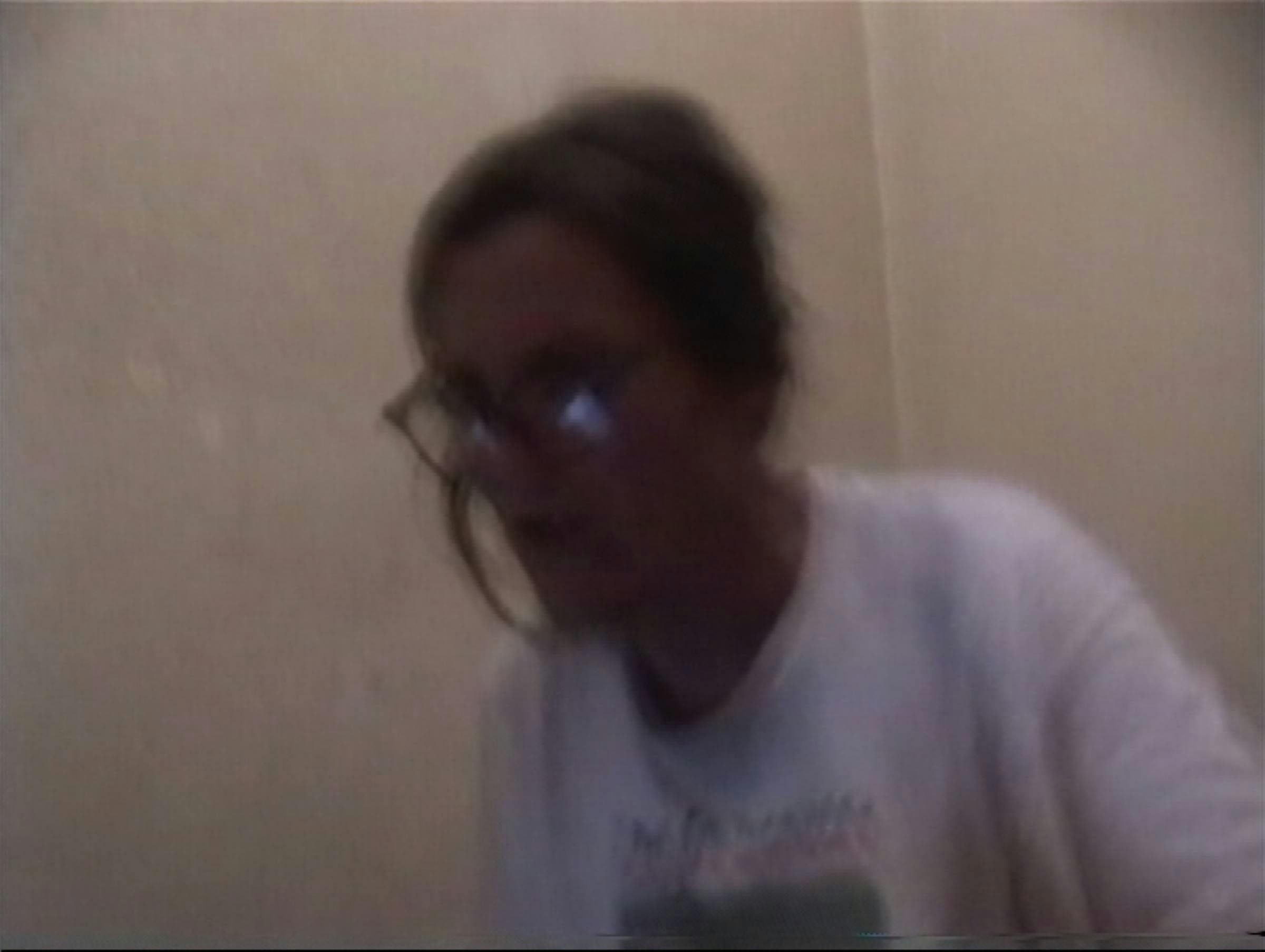 Image of someone wearing glasses and wearing a white t-shirt in a room with cream walls