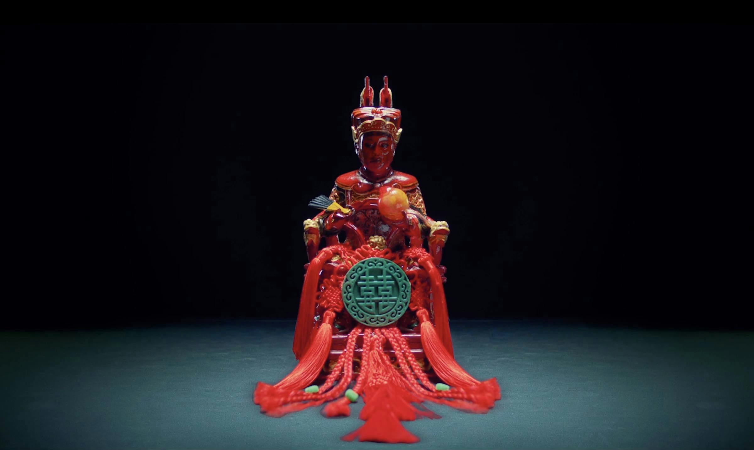 A Qing dynasty god in a darkened space. They are adorned with red tassels