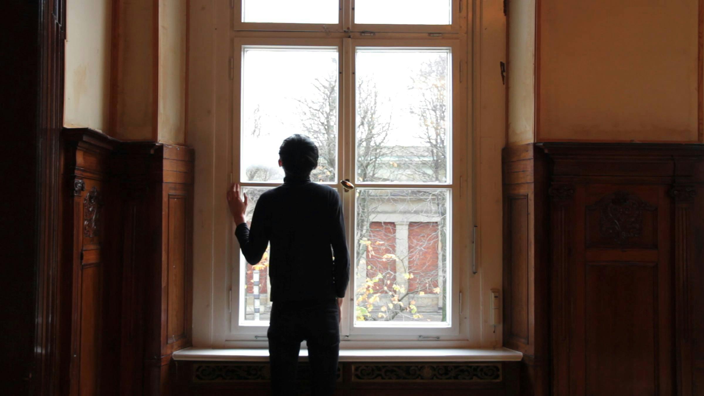 an image of the artist standing at a window 