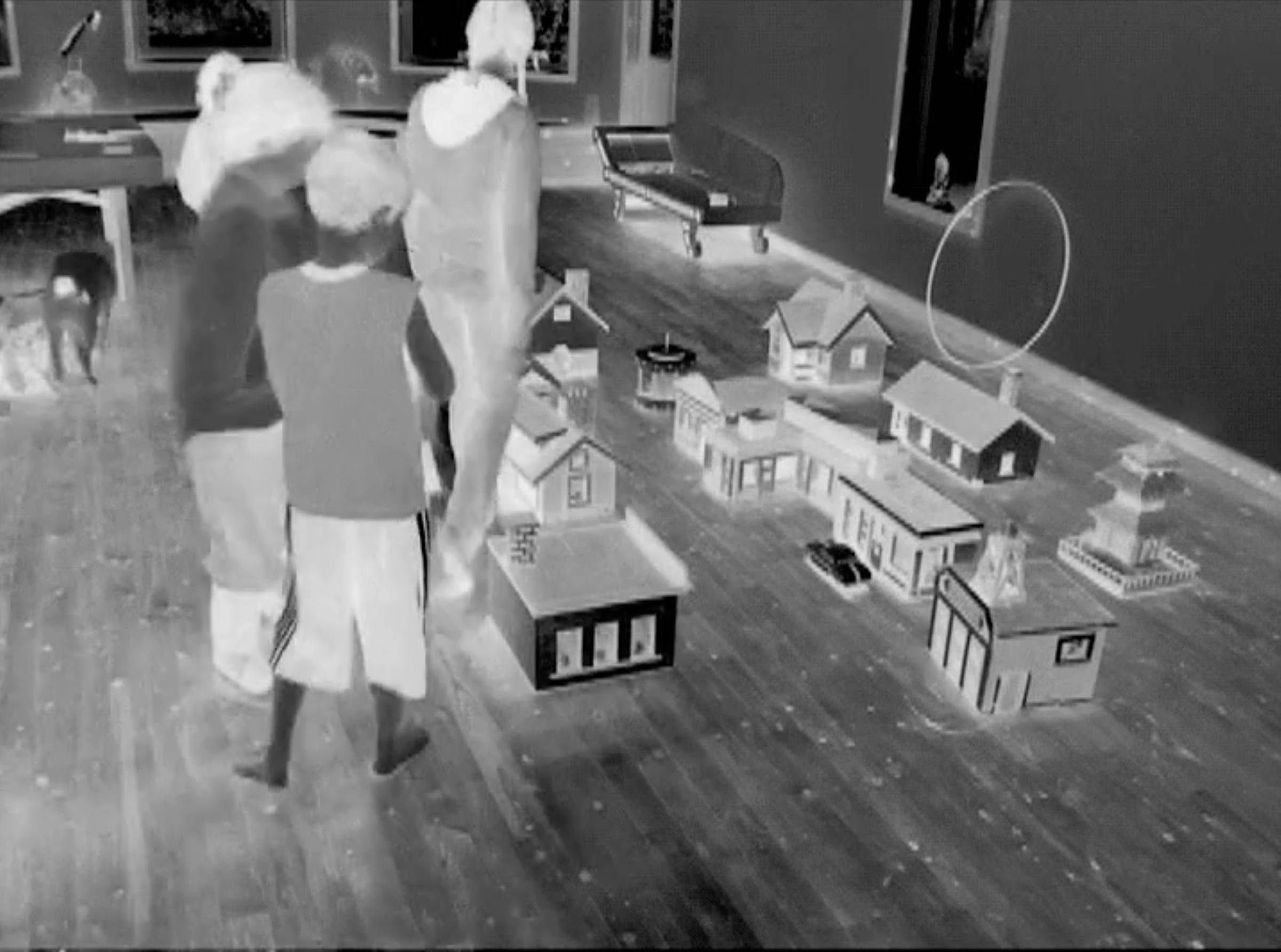 a black and white image of children in a room with a wooden floor looking at small wooden dolls' houses