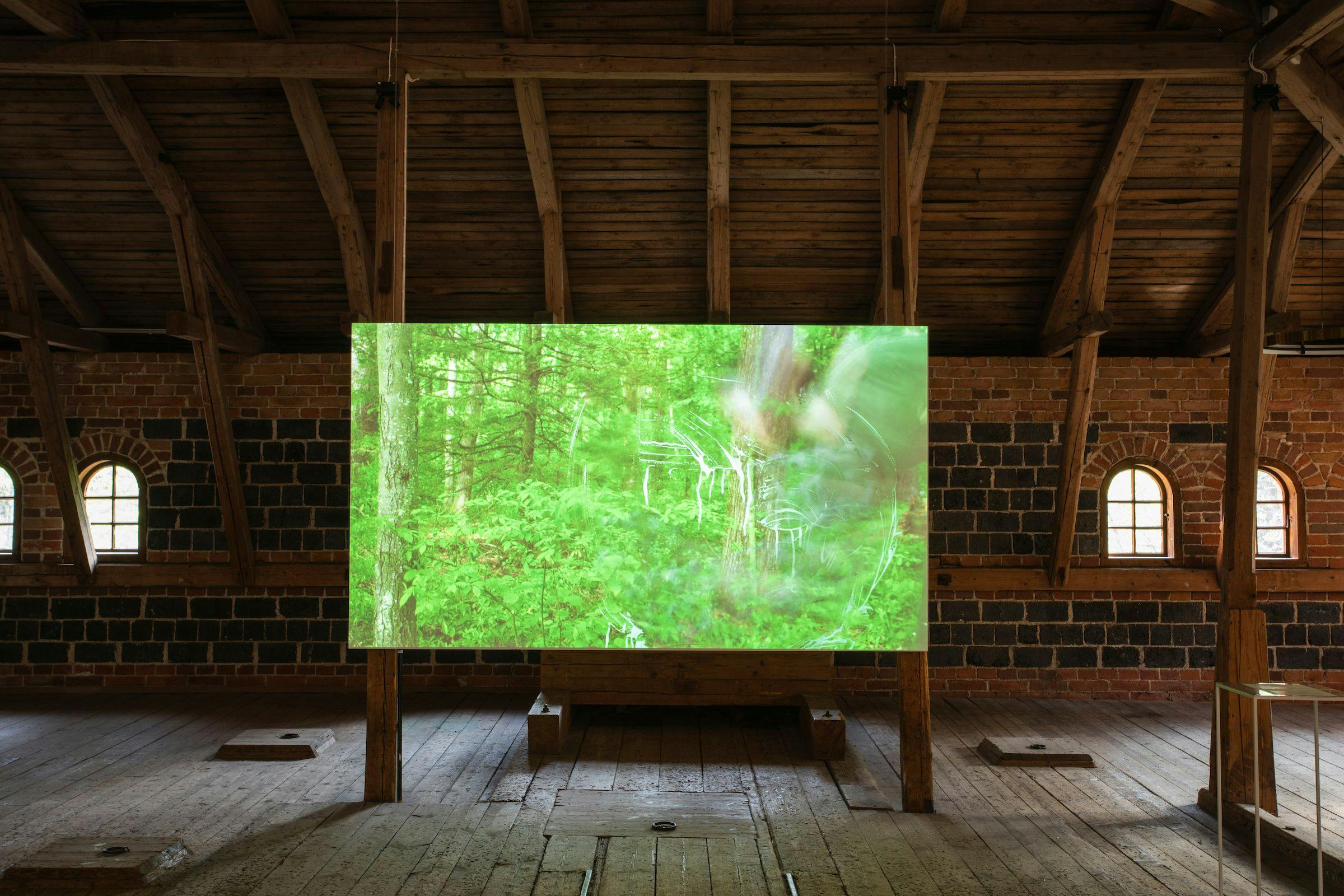 a video art work projected onto a wooden screen inside an unconventional gallery space that looks like the loft of a barn.
