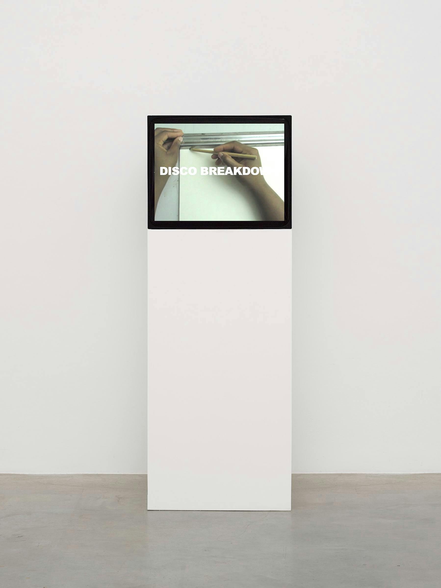 A TV on top of a white plinth in a white gallery space