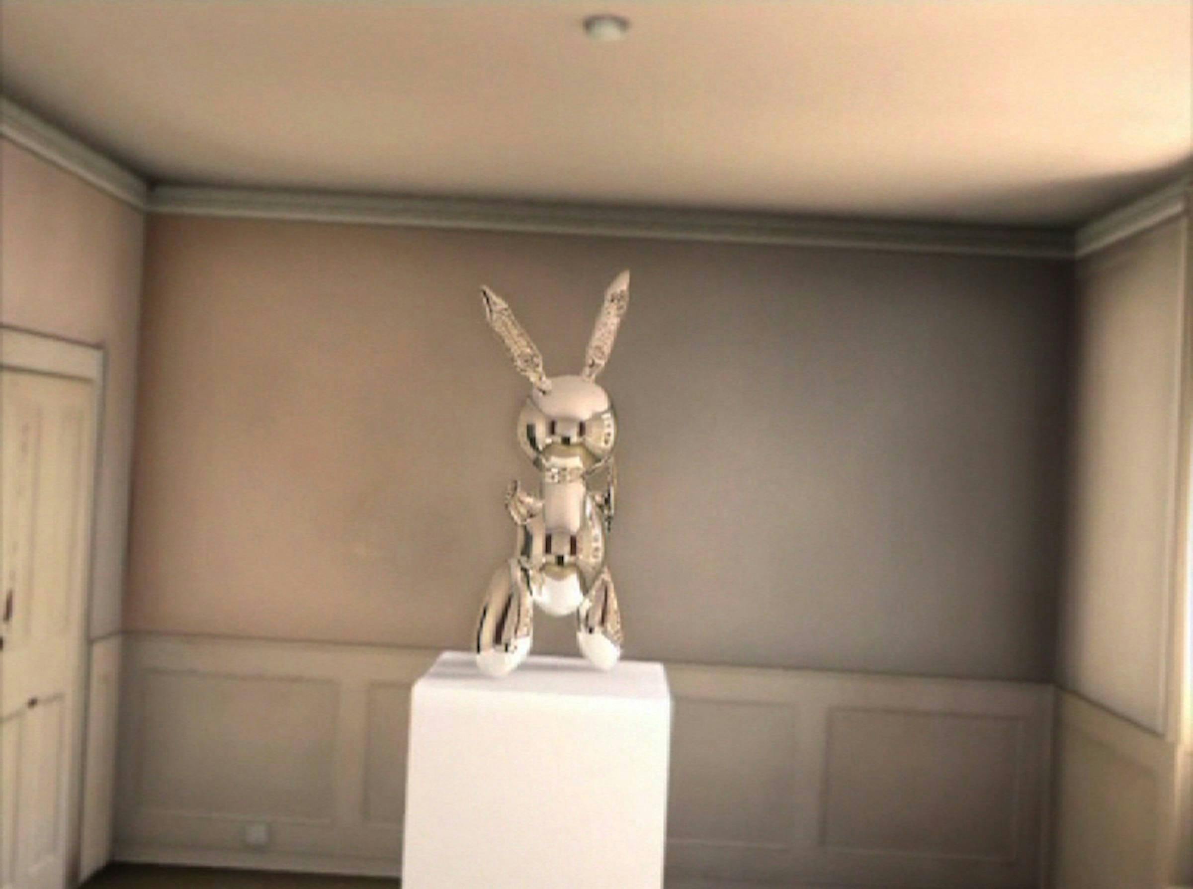 a digitally rendered image of a stainless steel Jeff Koons' rabbit on top of a plinth in a domestic room. You cannot see reflections of the camera in the stainless steel surface of the rabbit