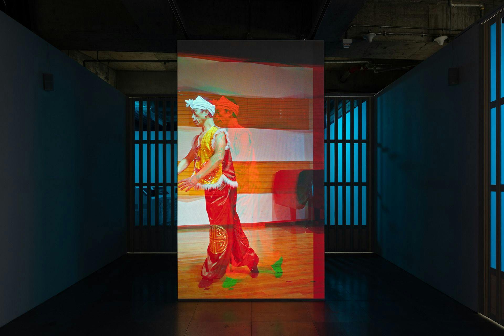 an art work projected in a gallery space on a screen that spans floor to ceiling but not wall to wall