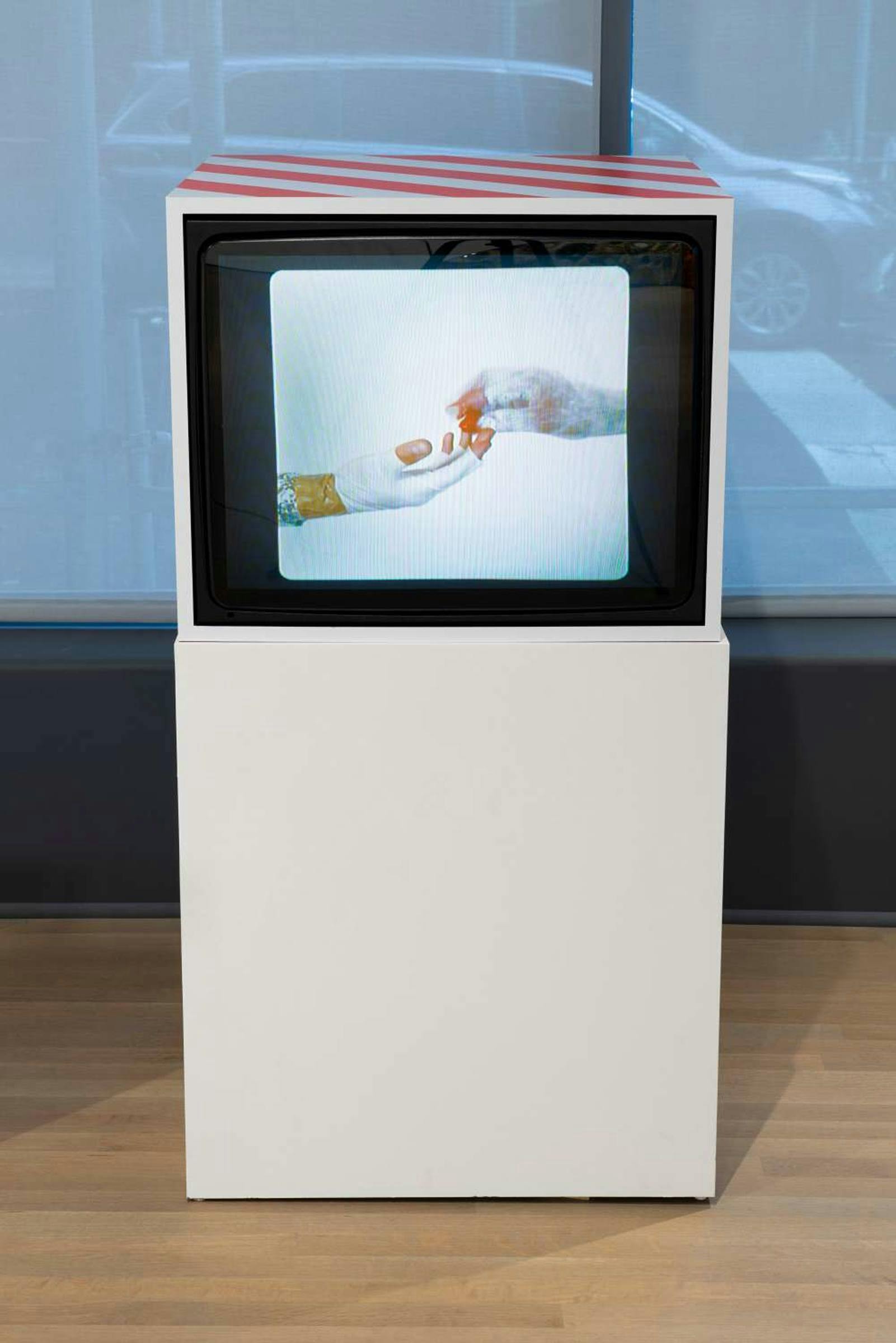 TV screen stands in white box stand with image of two hands reaching out to each other.