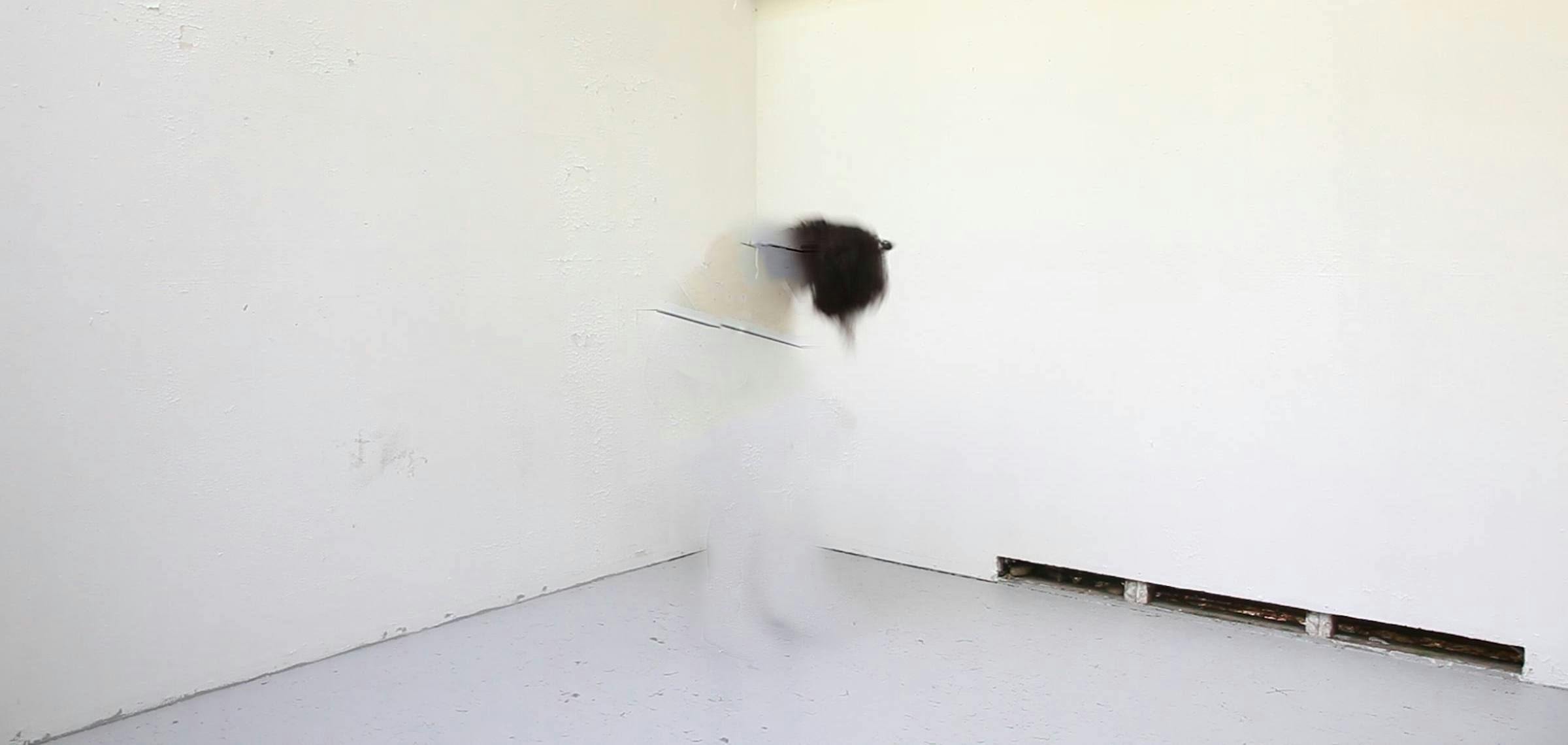 Image of an indistinct figure wearing all white dancing in a white gallery space