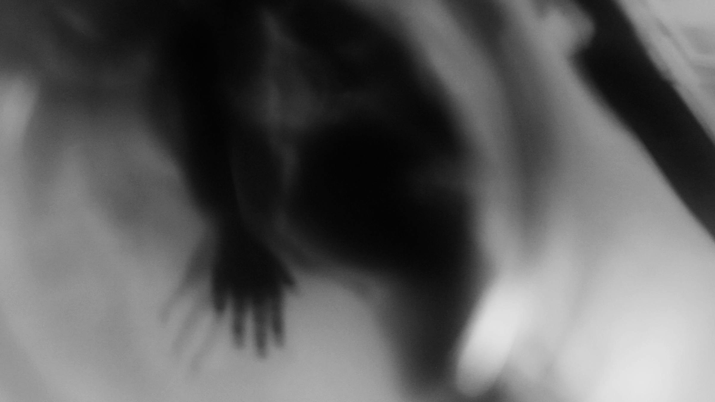 Black and white image of ghostly forms, including two outsretched hands.