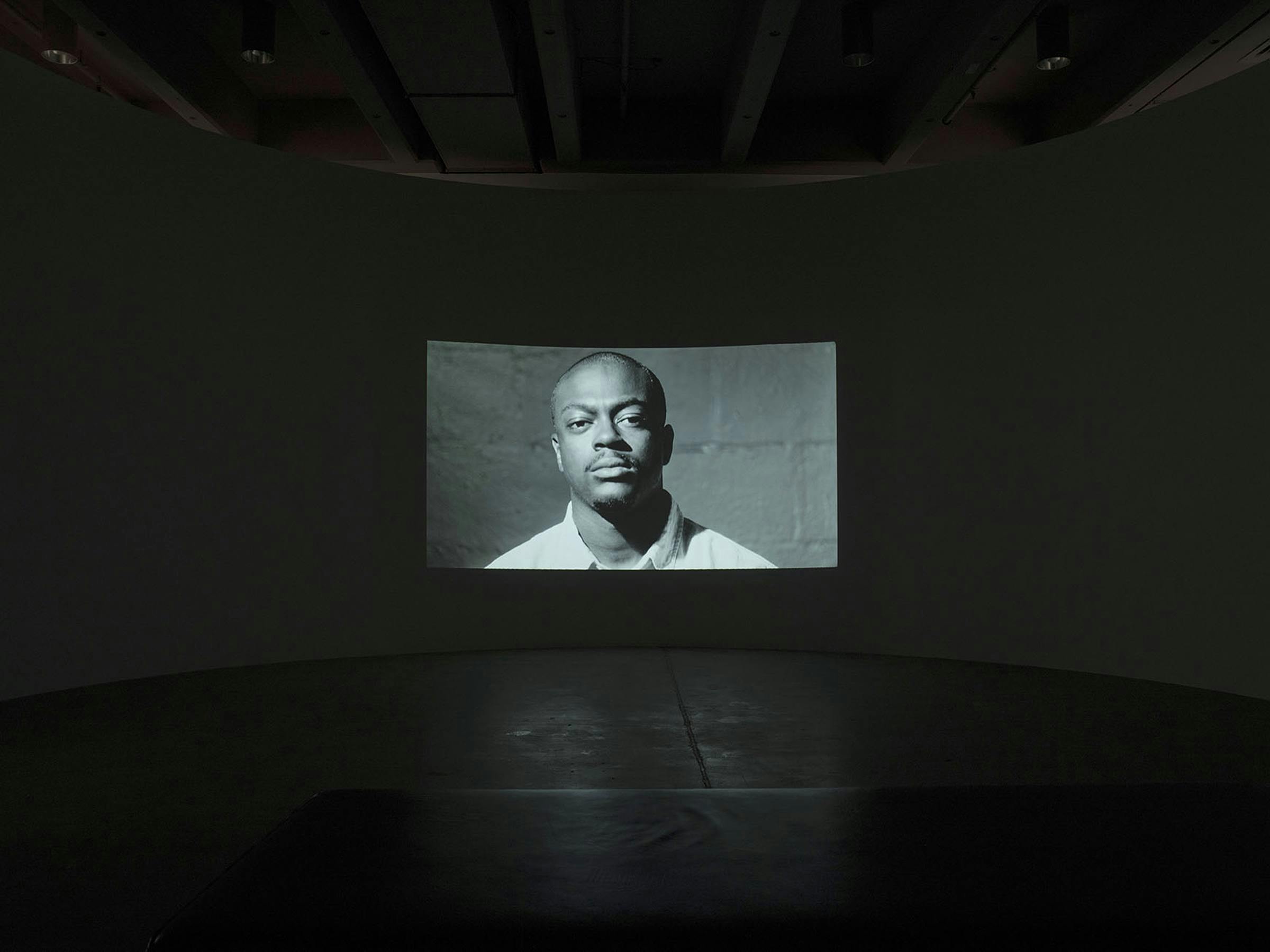 Image of an empty gallery space with large projection on one wall