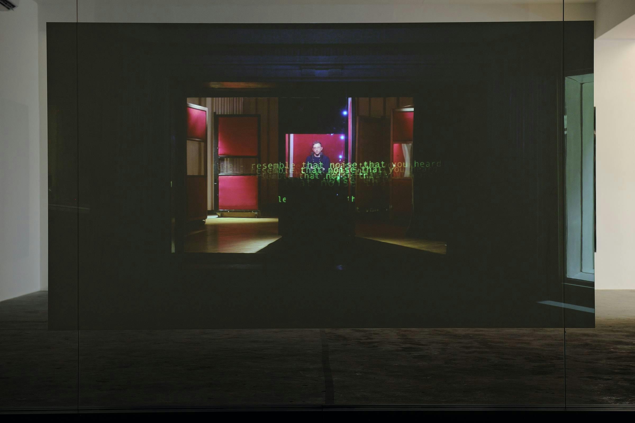 a video work projected on a free standing screen in a gallery