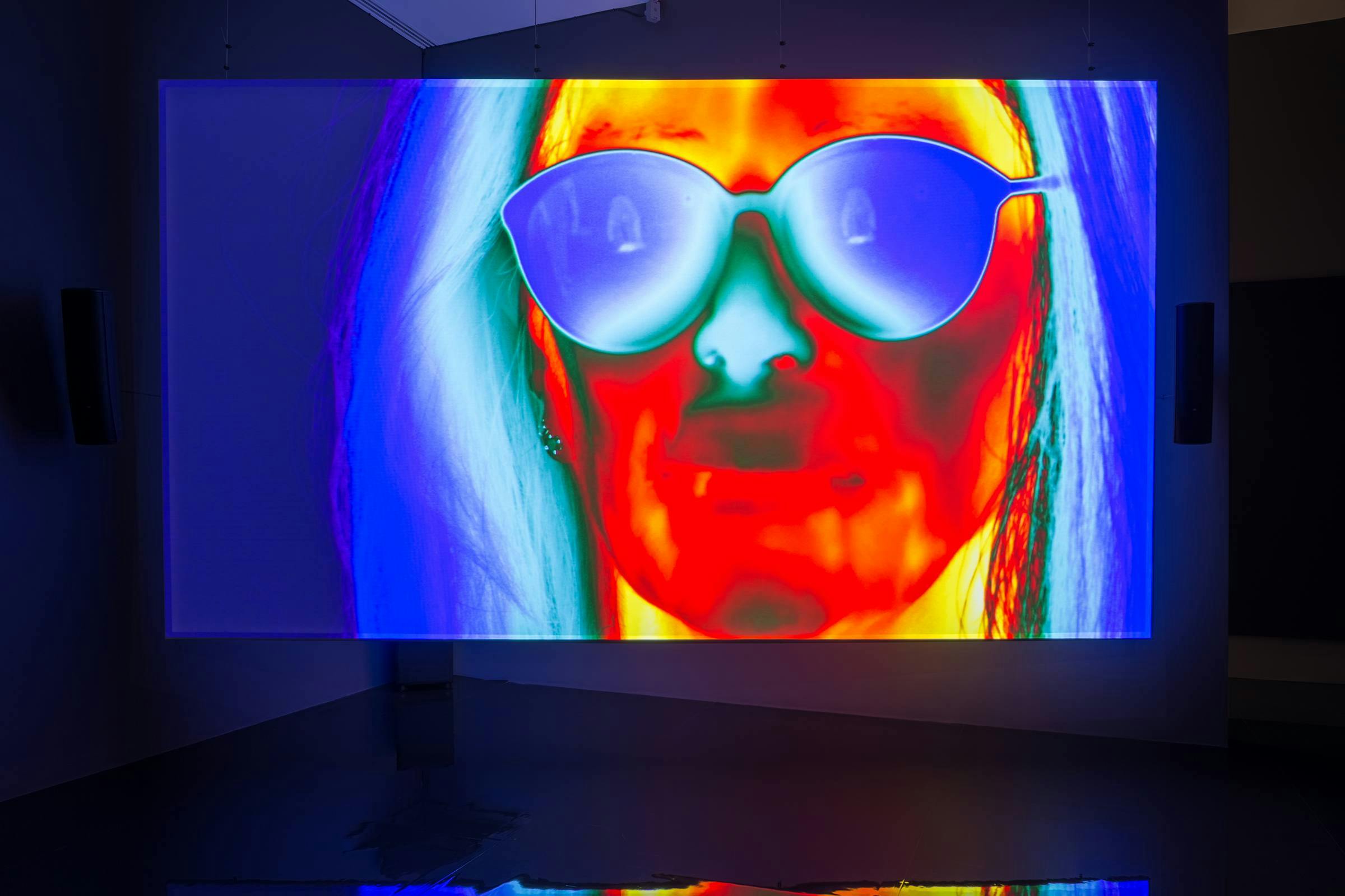 An image of face lit up by a infra red camera. They are wearing glasses