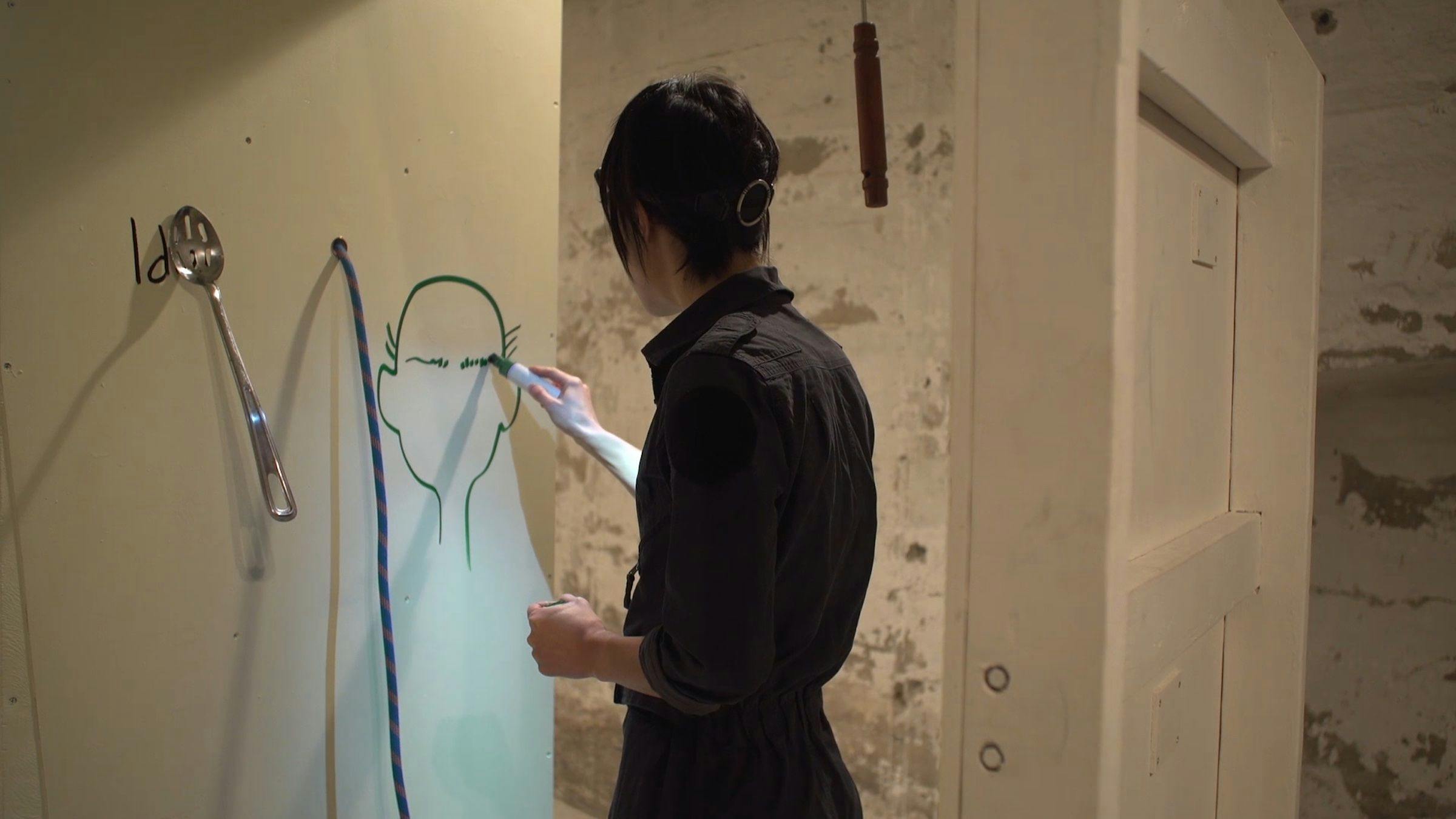 the artist drawing a face on a wall in a domestic space