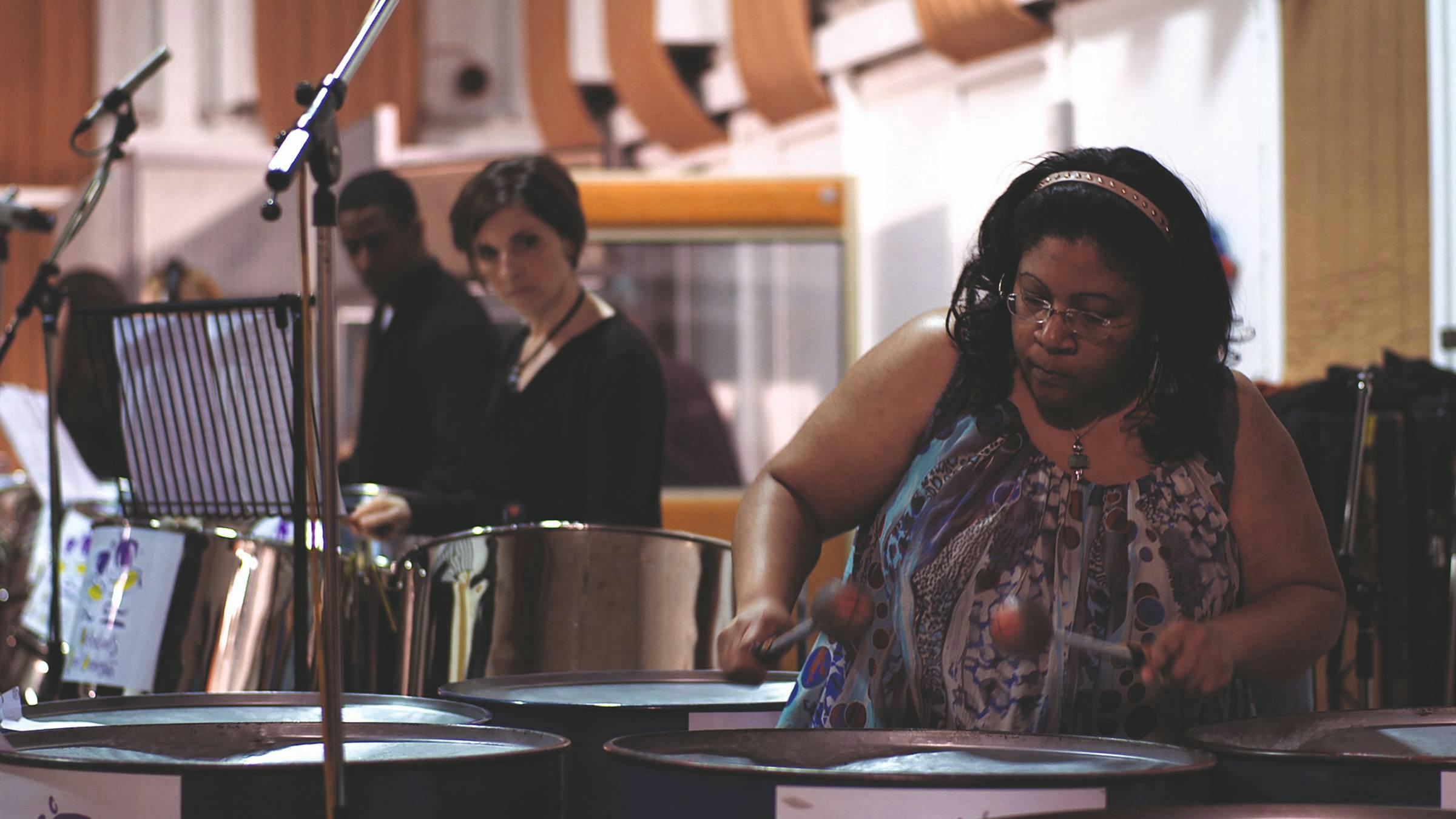an image of three people playing steel drums in a concert hall