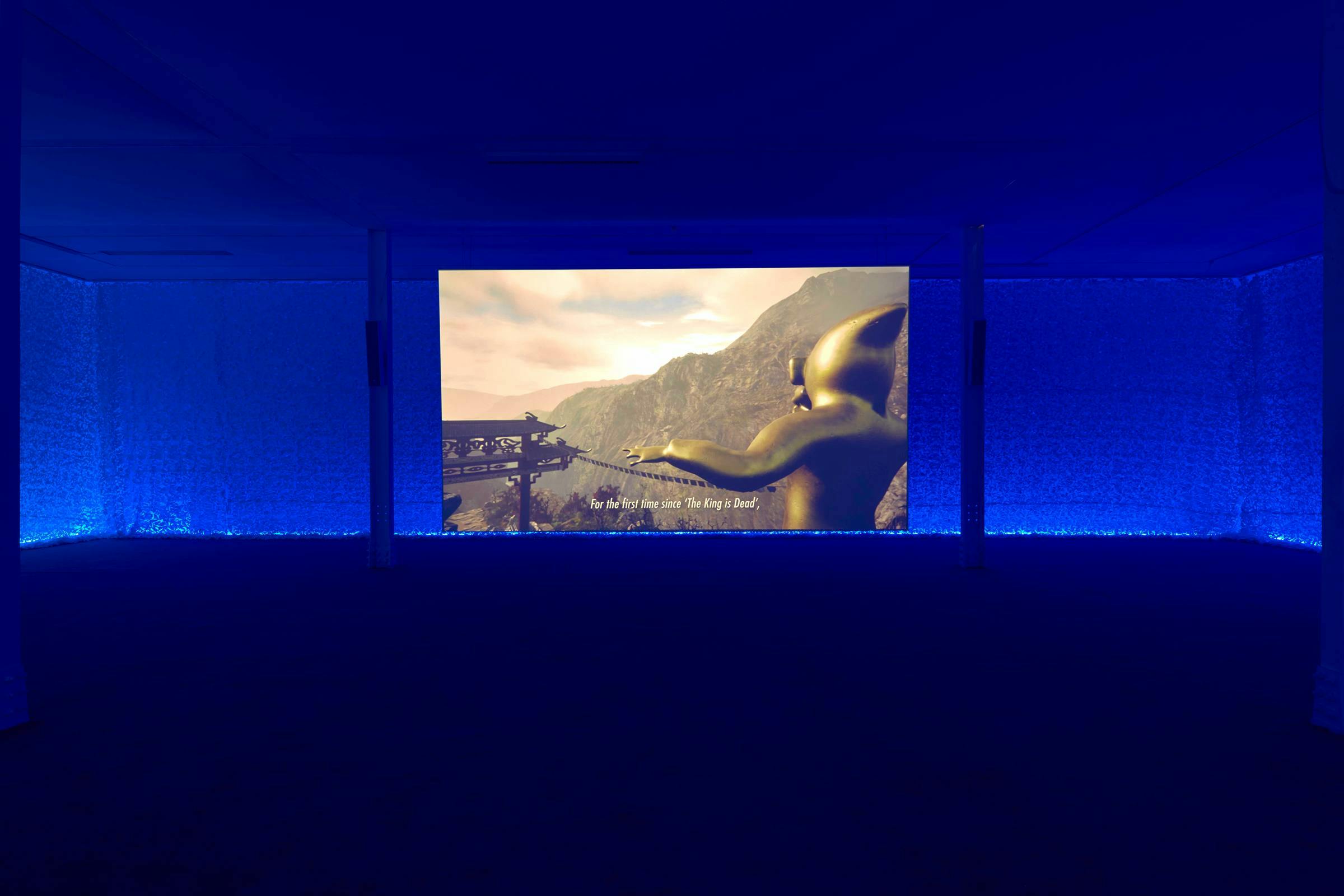 Image of a blue lit gallery space with an image projected large on the wall. 