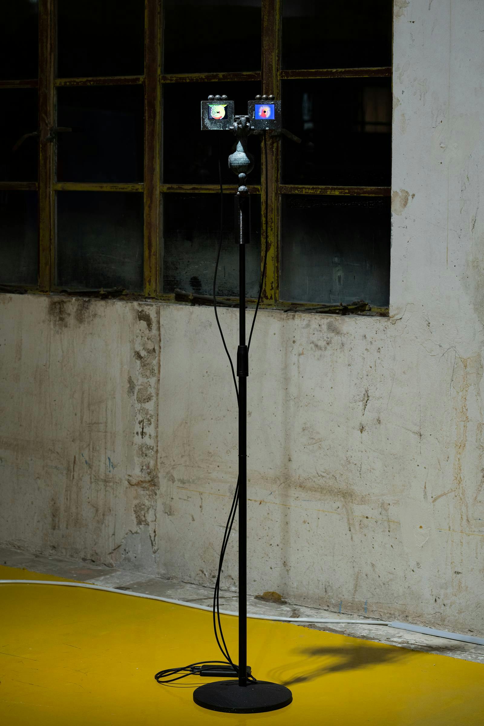 An image of the art work the messengers by Samson Young installed in an industrial building that has a yellow floor