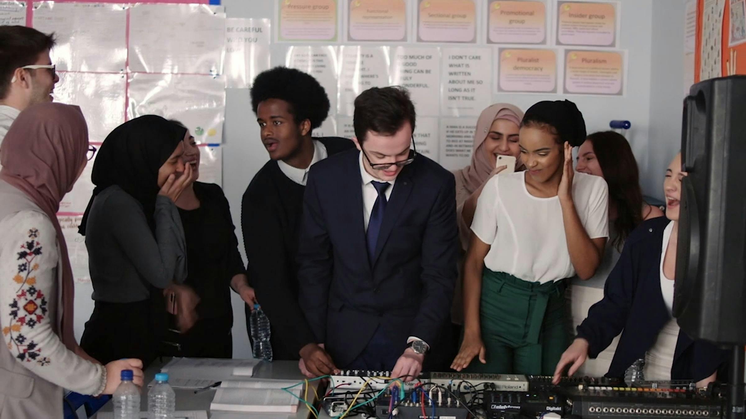 an image of a group of school children and their teacher playing on synthesizers