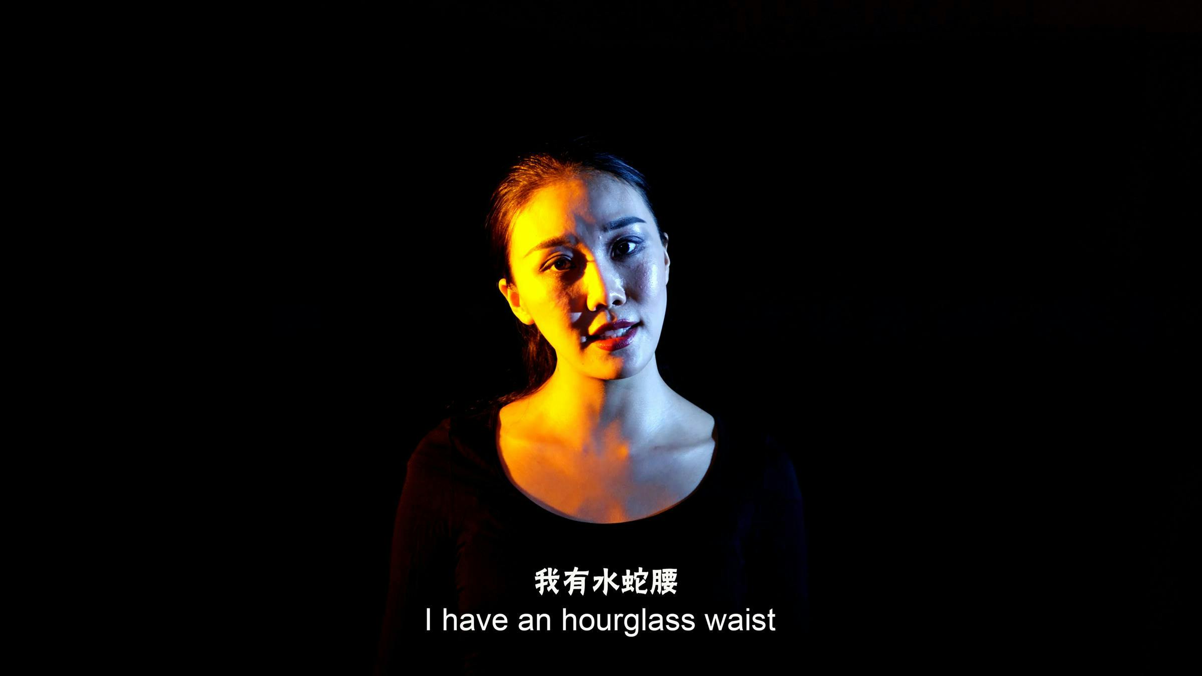 The face of a  Chinese woman with her head titled to the side. The back ground is black and a white subtitle says 'I have an hourglass waist' above this the Chinese translation is written.